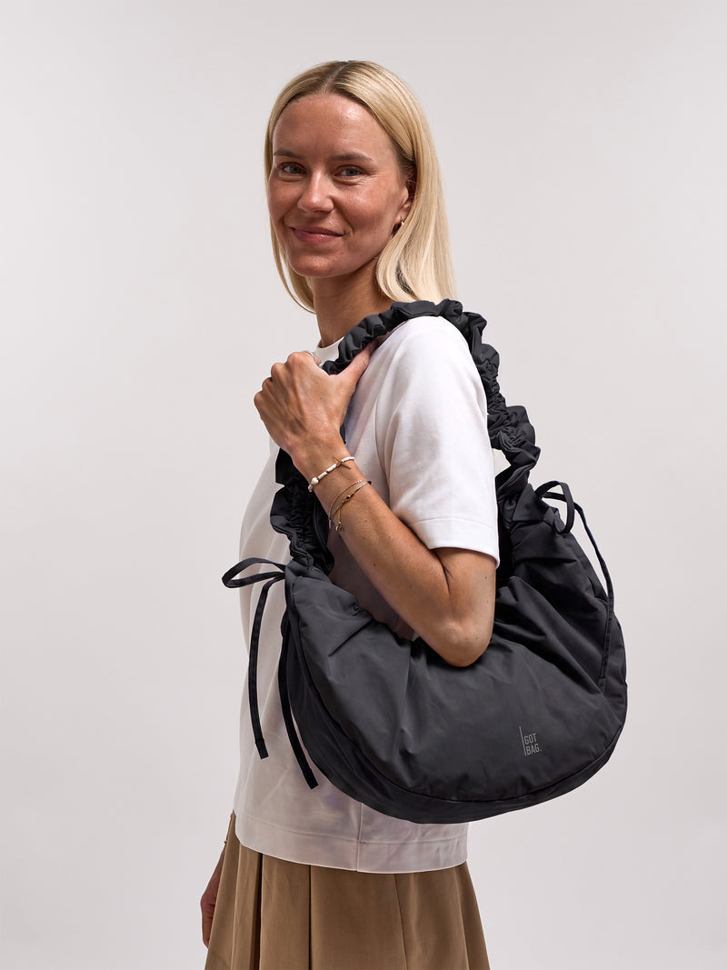 MOON BAG BOW Tasche in black (Schwarz) von einer Frau über der Schulter getragen.