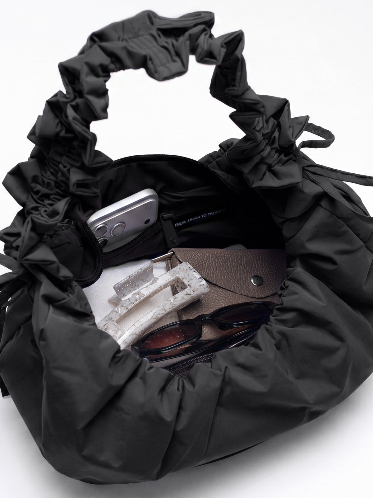 MOON BAG BOW Tasche in black (Schwarz) Innenansicht, gefüllt mit Smartphone, Sonnenbrille und Geldbörse.