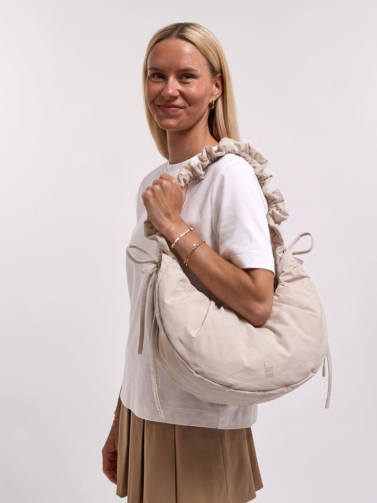 MOON BAG BOW Tasche in soft shell (warmes Cremeweiß) von einer Frau über der Schulter getragen.