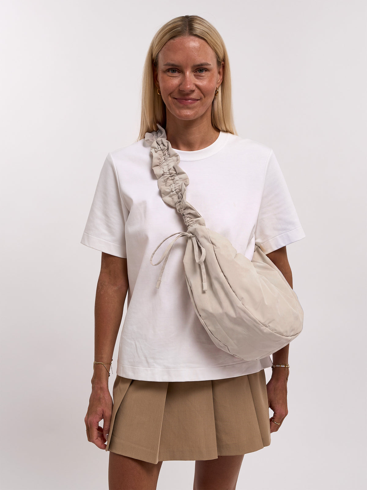 MOON BAG BOW Tasche in soft shell (warmes Cremeweiß) von einer Frau crossbody getragen.
