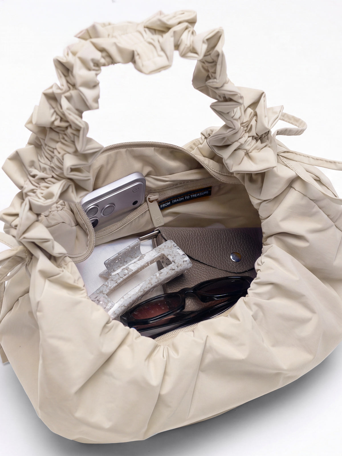 MOON BAG BOW Tasche in soft shell (warmes Cremeweiß) von innen gefüllt mit persönlichen Gegenständen.