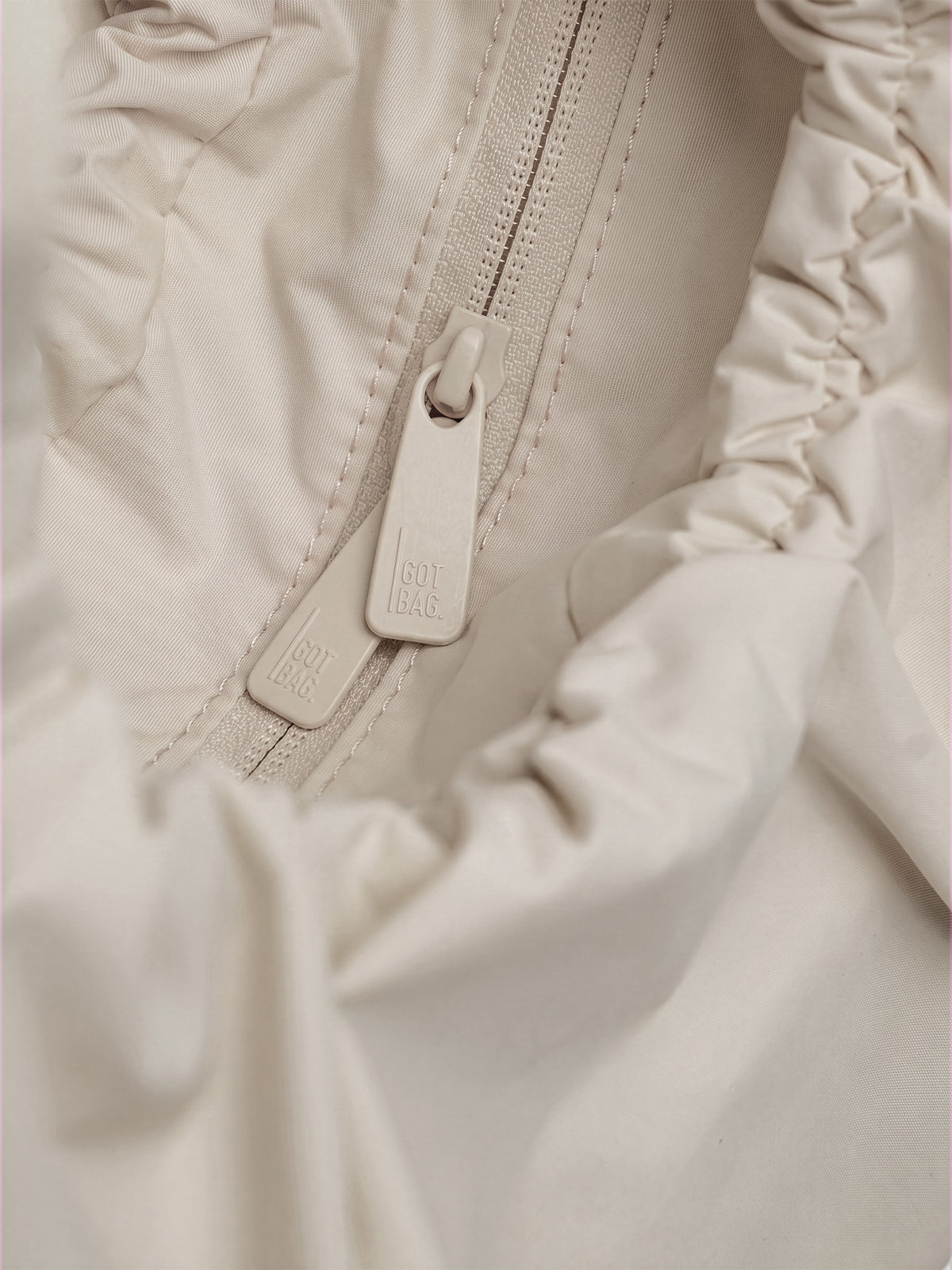MOON BAG BOW Tasche in soft shell (warmes Cremeweiß), Detailaufnahme des Reißverschlusses mit GOT BAG. Schriftzug.