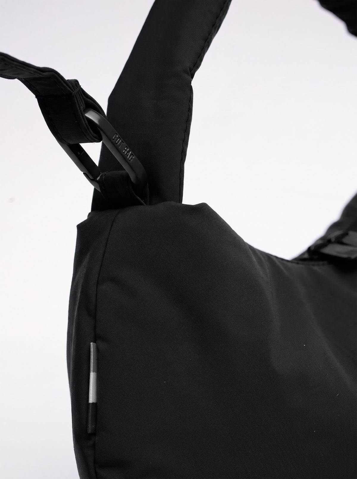 CLOUD BEAD BAG Tasche in black (Schwarz) Detailaufnahme des Gurtes mit Karabiner und Reflektorstreifen.