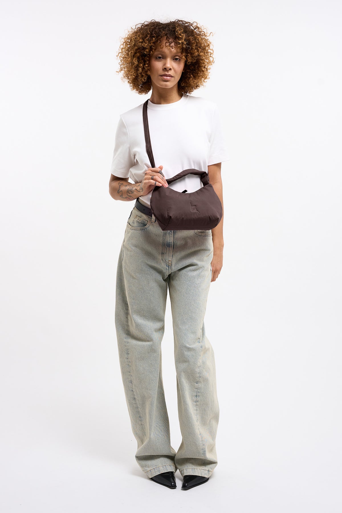 CLOUD BEAD BAG Tasche in sea lion (dunkles Schokobraun) von einer Frau crossbody getragen.