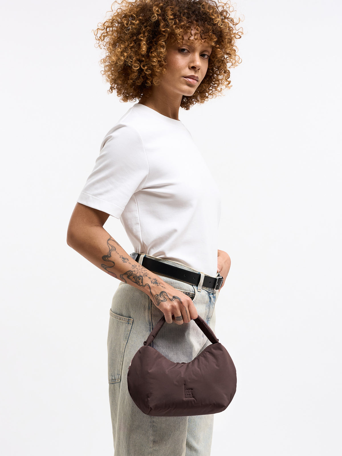 CLOUD BEAD BAG Tasche in sea lion (dunkles Schokobraun) von einer Frau in der Hand gehalten.