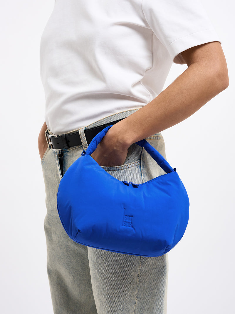 CLOUD BEAD BAG Tasche in cobalt (leuchtendes Kobaltblau) von einer Frau in der Hand gehalten.