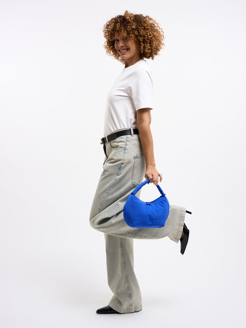 CLOUD BEAD BAG Tasche in cobalt (leuchtendes Kobaltblau) von einer Frau in der Hand gehalten.