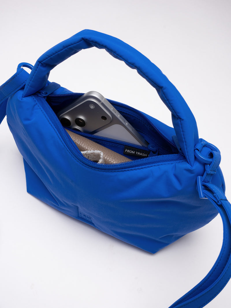 CLOUD BEAD BAG Tasche in cobalt (leuchtendes Kobaltblau), Detailaufnahme des Innenraums mit Handy und Kleinigkeiten.