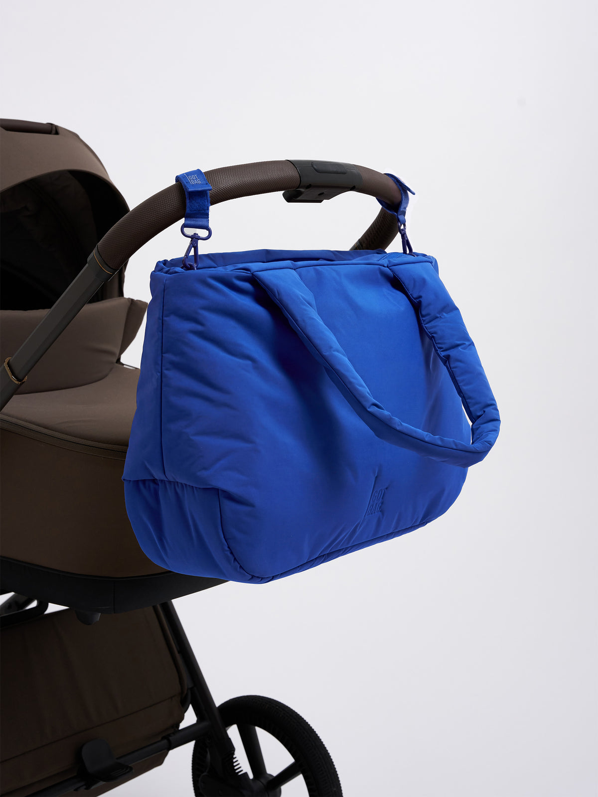 CLOUD HORIZON TOTE BAG Tasche in cobalt (leuchtendes Kobaltblau) an einem Kinderwagen-Griff hängend.