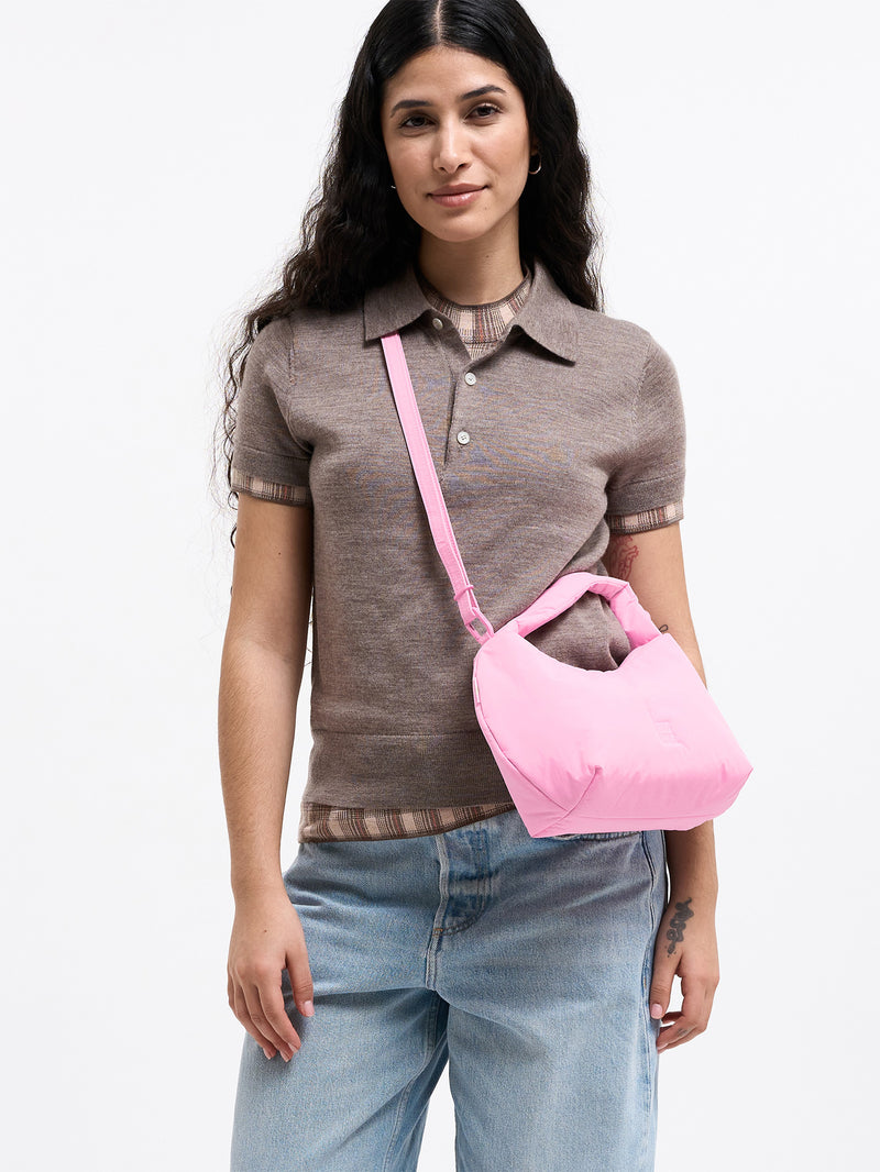 CLOUD BEAD BAG Tasche in sea rose (sattes Pastell-Rosa) von einer Frau crossbody getragen.