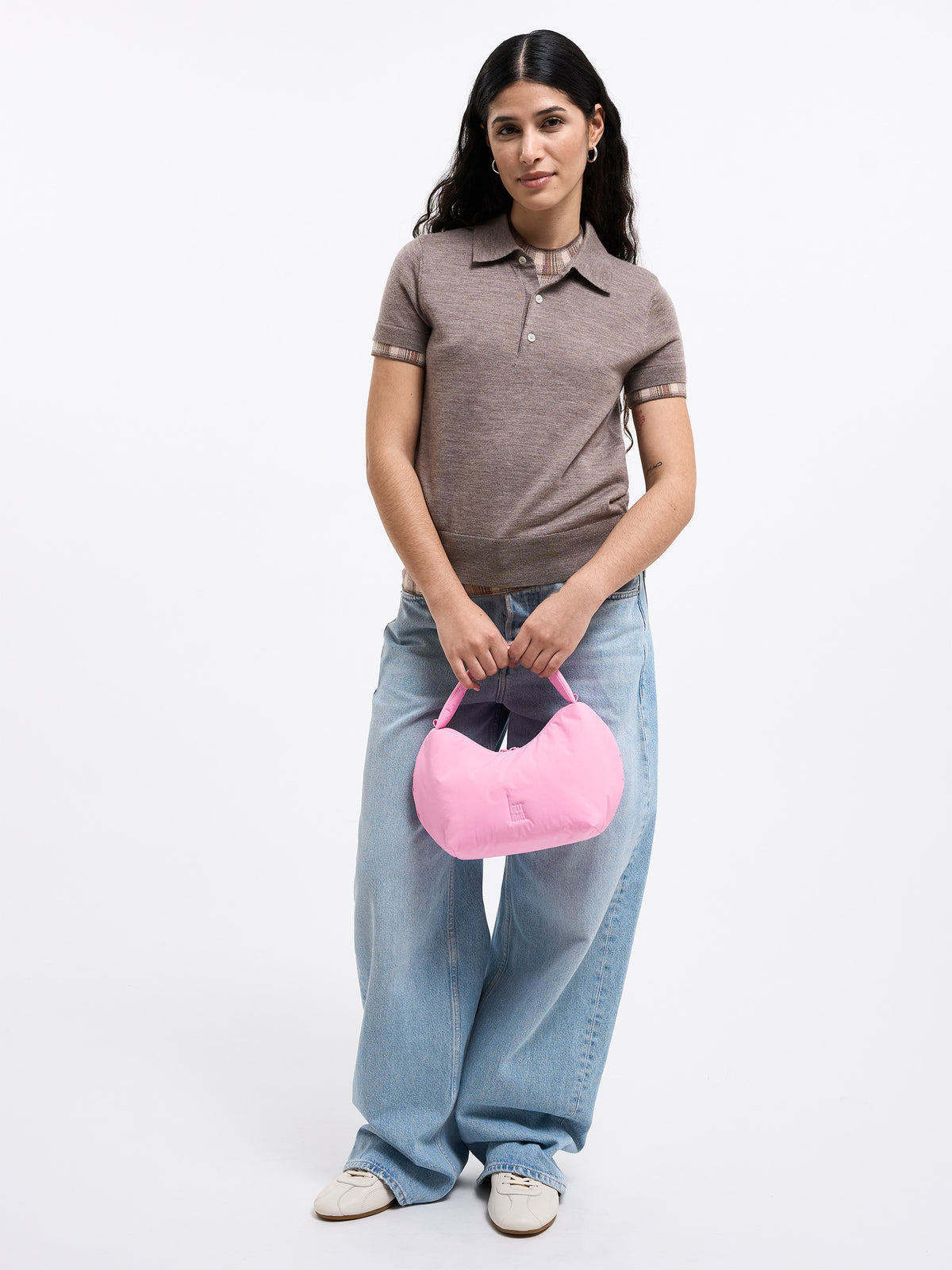 CLOUD BEAD BAG Tasche in sea rose (sattes Pastell-Rosa) von einer Frau in der Hand gehalten.