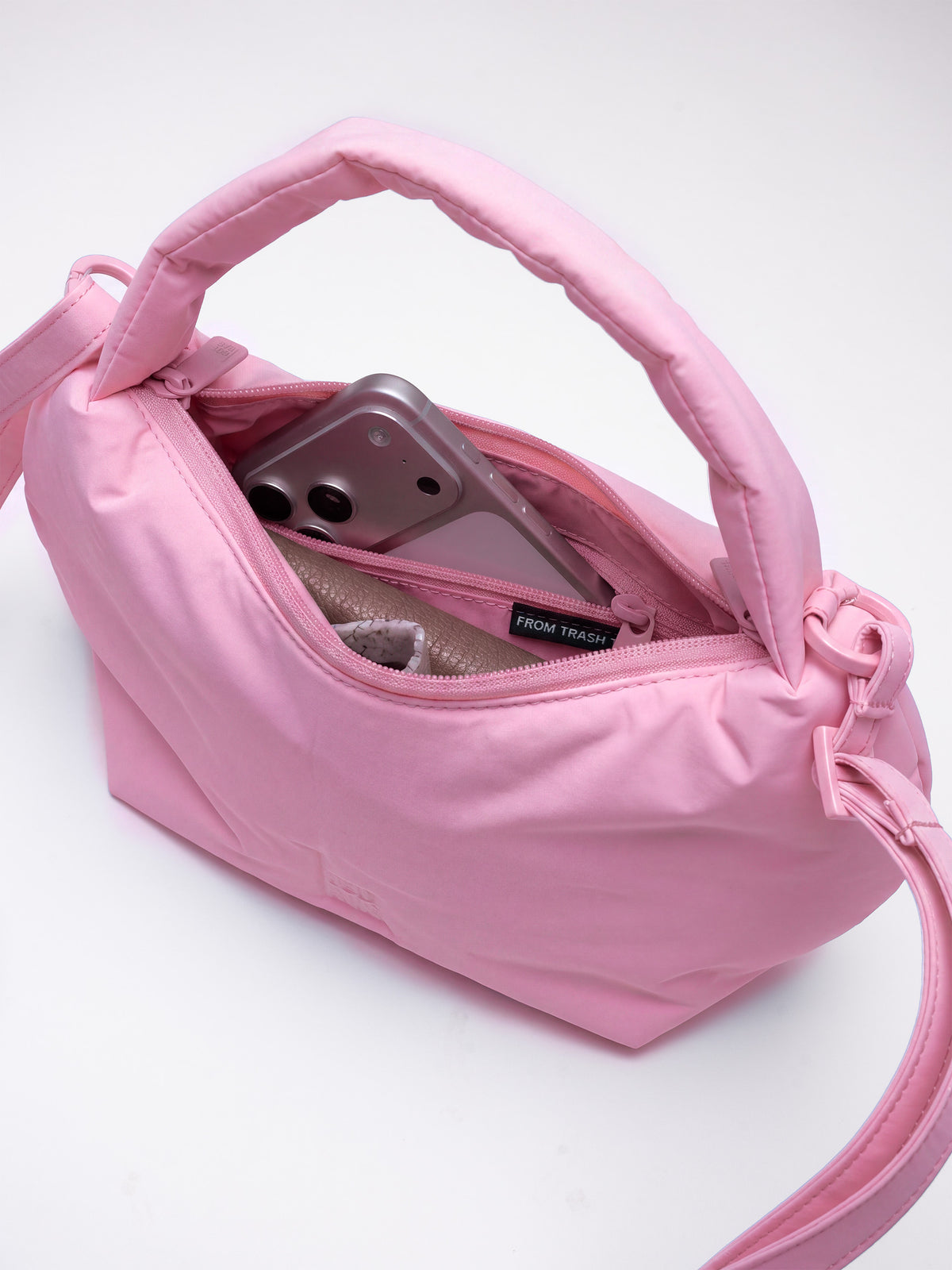 CLOUD BEAD BAG Tasche in sea rose (sattes Pastell-Rosa), gefüllt mit Smartphone und Geldbörse.