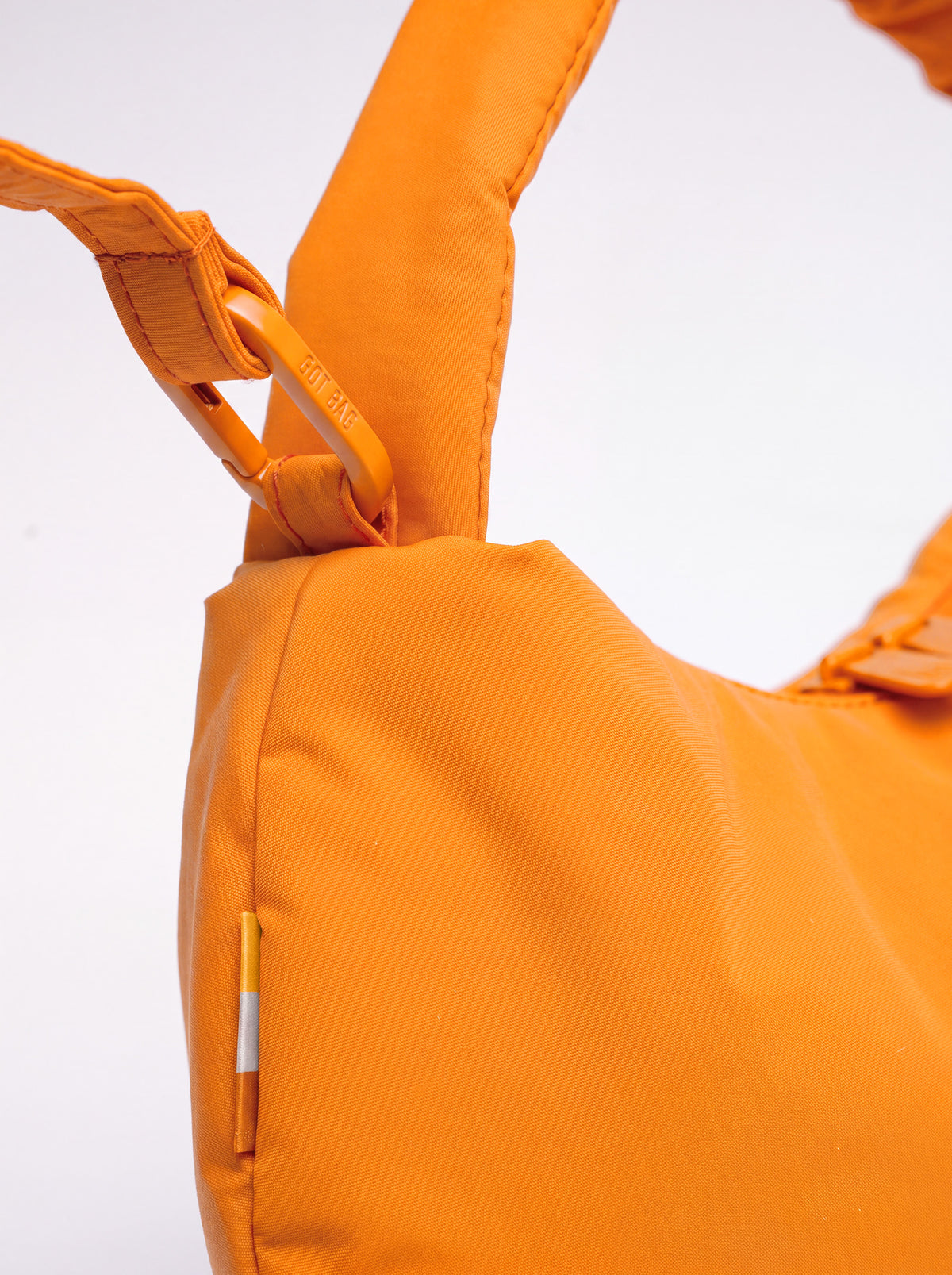 CLOUD BEAD BAG Tasche in clownfish (leuchtendes Orange-Gelb), Detailaufnahme des Trägers und Karabiners.