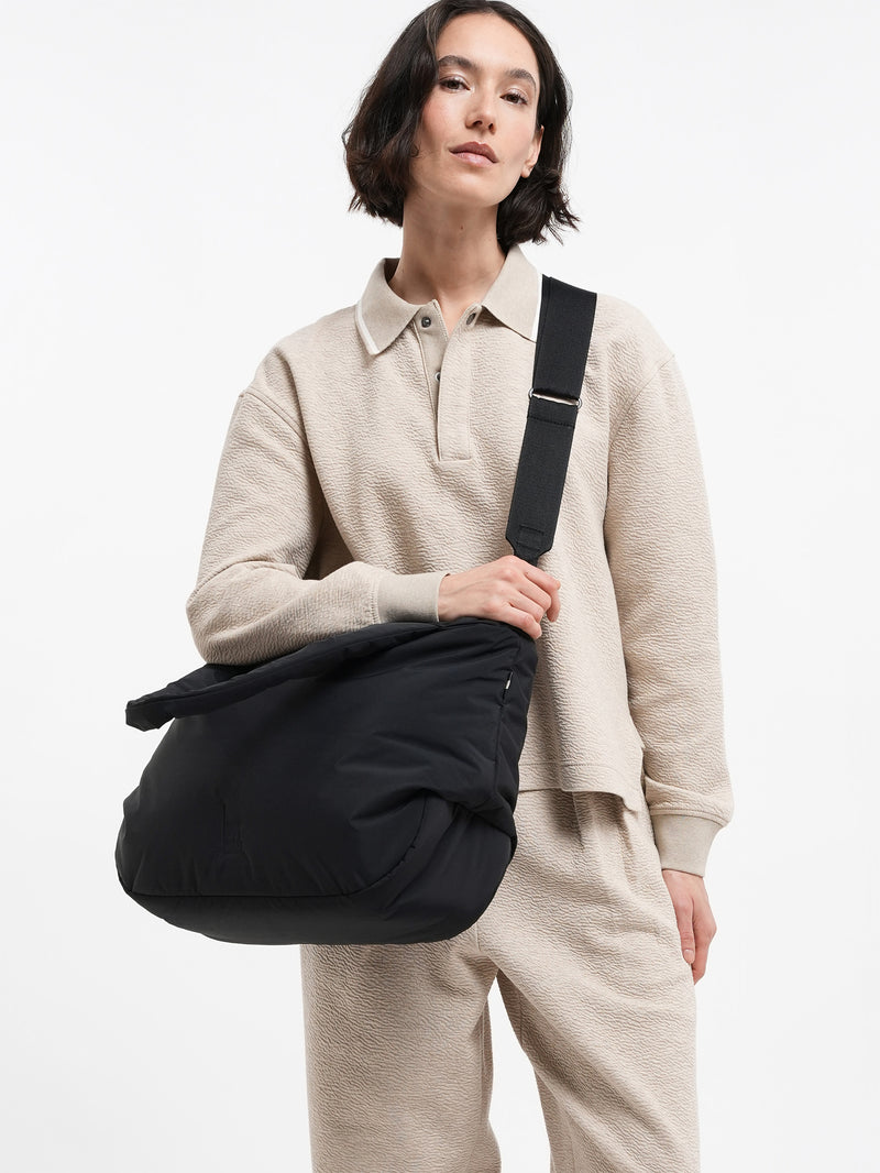 CLOUD HORIZON TOTE BAG Tasche in black (Schwarz) von einer Frau über der Schulter getragen.
