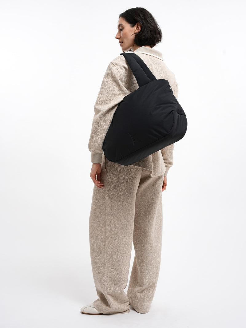CLOUD HORIZON TOTE BAG Tasche in black (Schwarz) von einer Frau über der Schulter getragen.