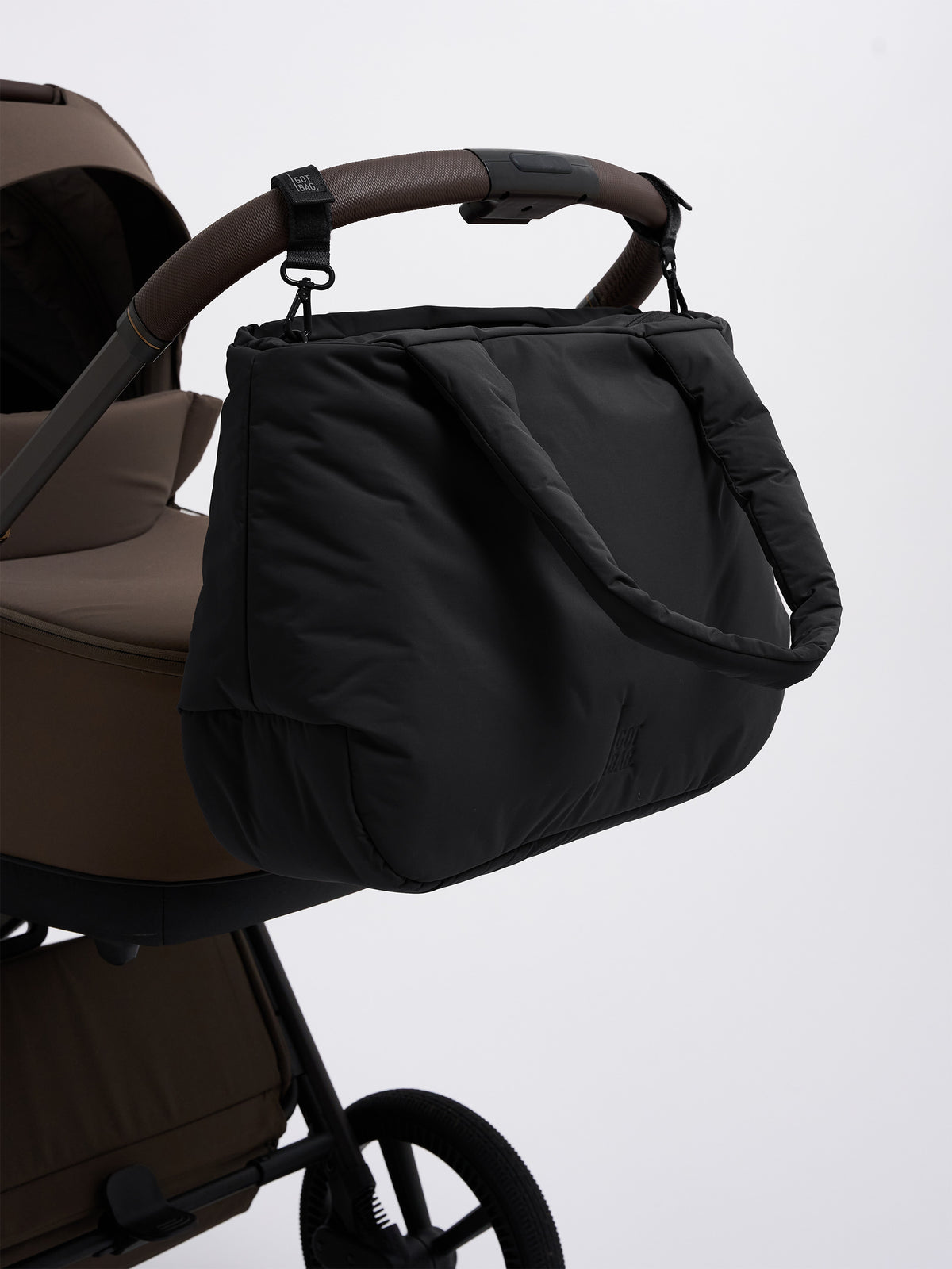 CLOUD HORIZON TOTE BAG Tasche in black (Schwarz), mit Gurten an einem Kinderwagen befestigt.