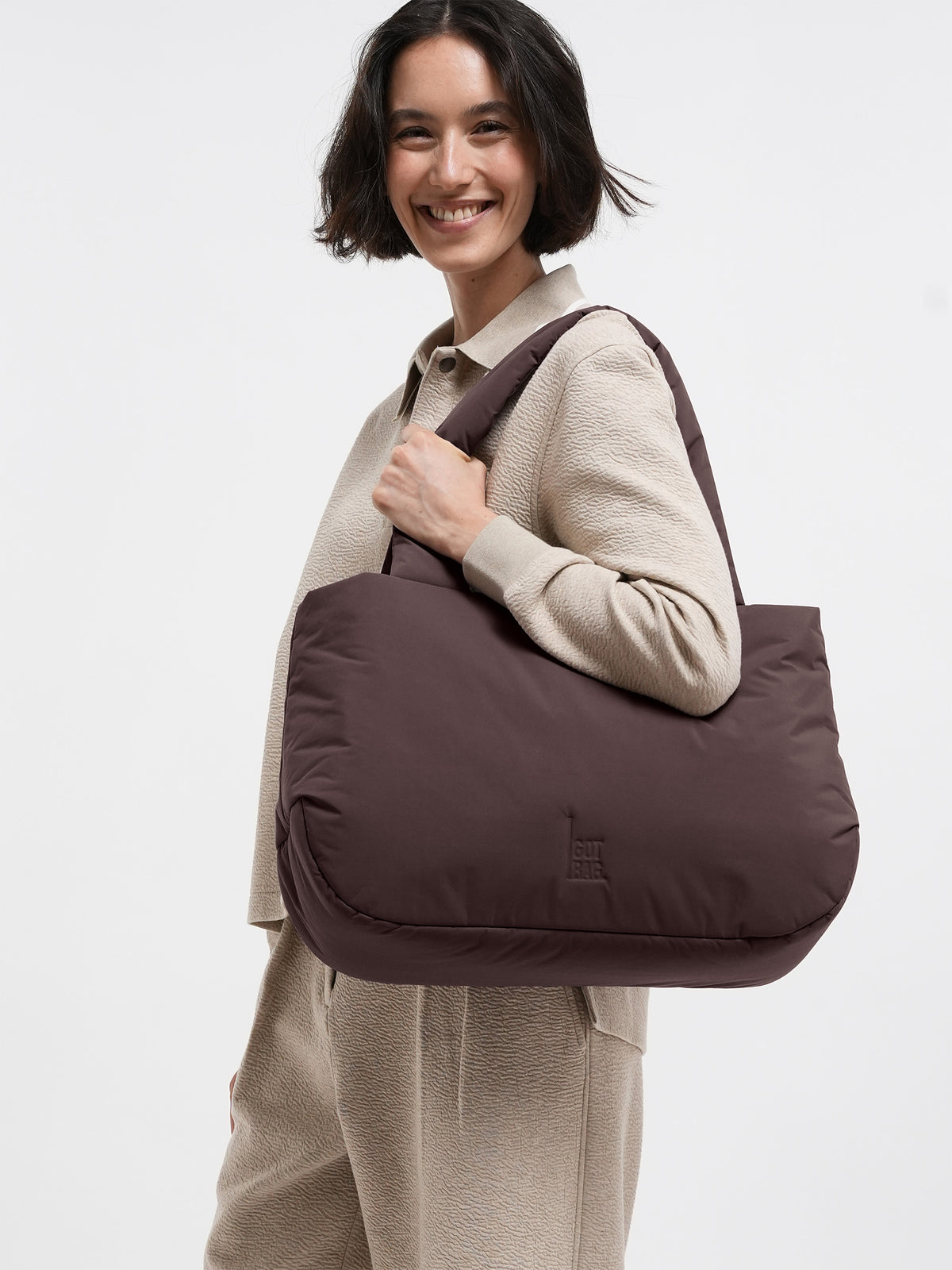 CLOUD HORIZON TOTE BAG Tasche in sea lion (dunkles Schokobraun) von einer Frau über der Schulter getragen.