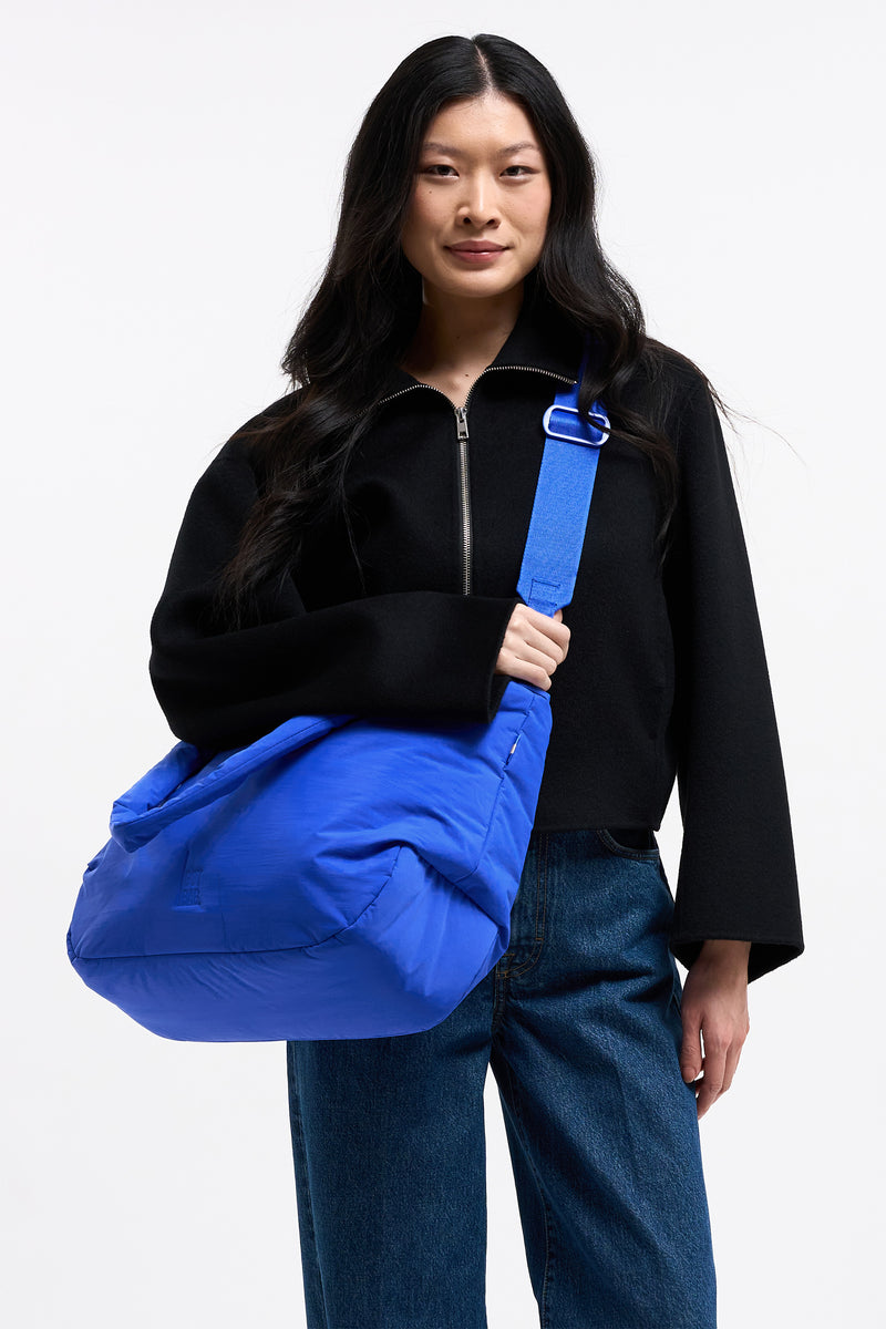 CLOUD HORIZON TOTE BAG Tasche in cobalt (leuchtendes Kobaltblau) von einer Frau über der Schulter getragen.