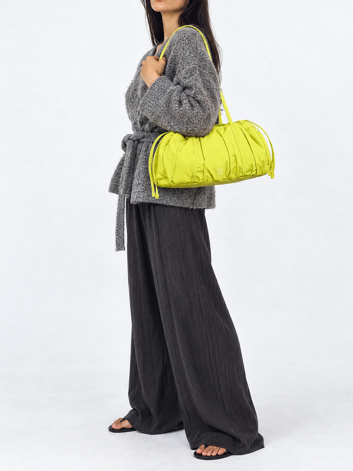 SHELLY SHOULDER BAG Tasche in seagrass (leuchtendes Gelb-Grün) von einer Frau über der Schulter getragen.