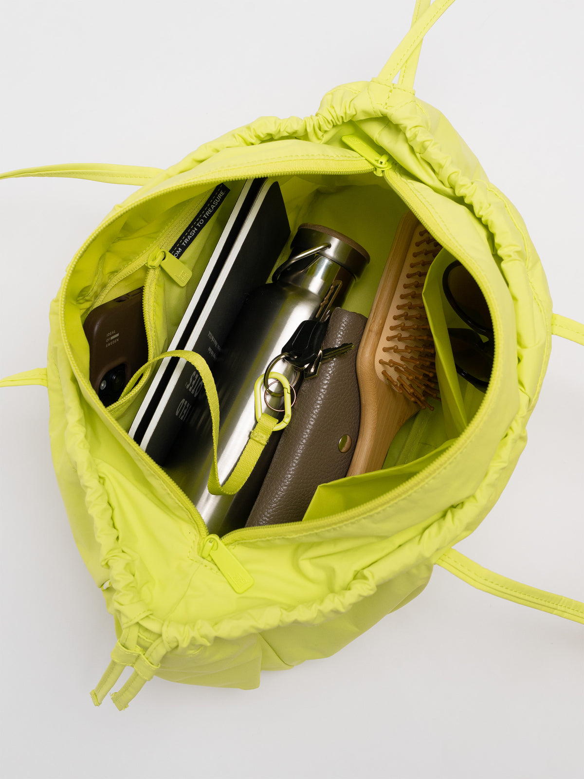 SHELLY SHOULDER BAG Tasche in seagrass (leuchtendes Gelb-Grün) mit Blick in das gefüllte Innere.