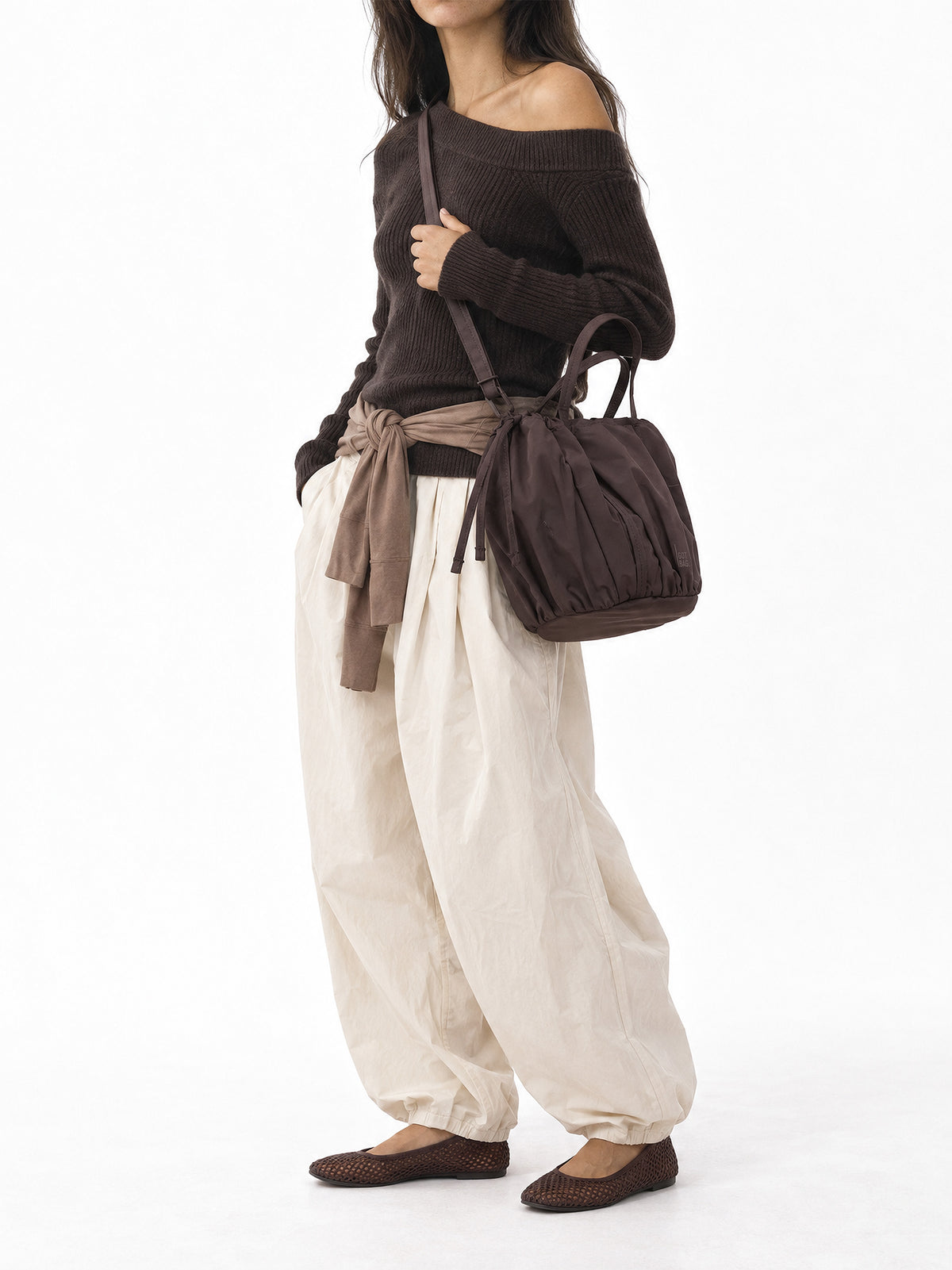 SHELLY BUCKET BAG Tasche in sea lion (dunkles Schokobraun) von einer Frau crossbody getragen.