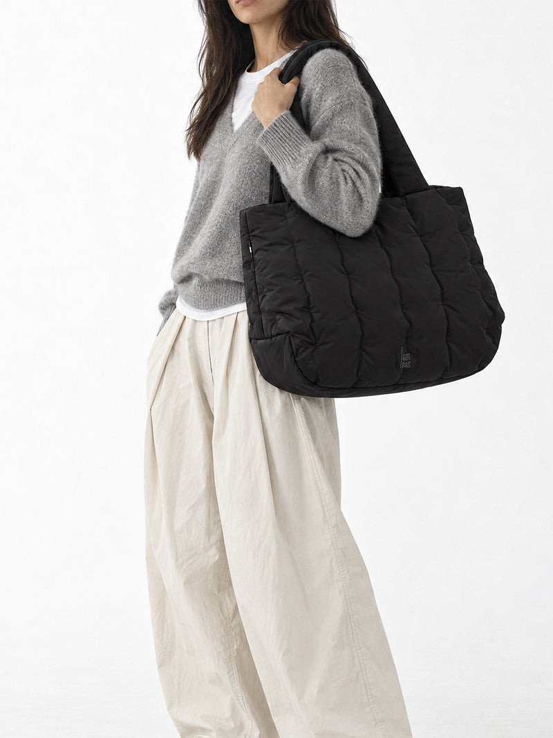 LOOMI HORIZON TOTE BAG Tasche in black (Schwarz) von einer Frau über der Schulter getragen.