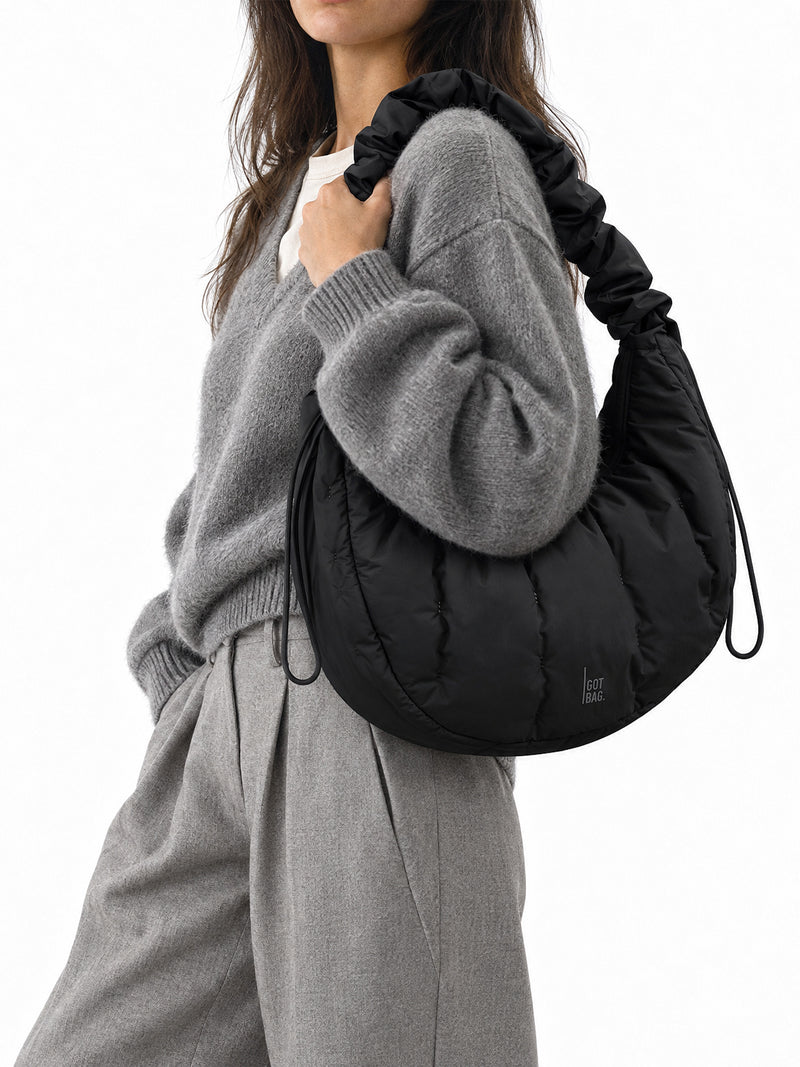 LOOMI MOON BAG RUFFLE Tasche in black (Schwarz) von einer Frau über der Schulter getragen.