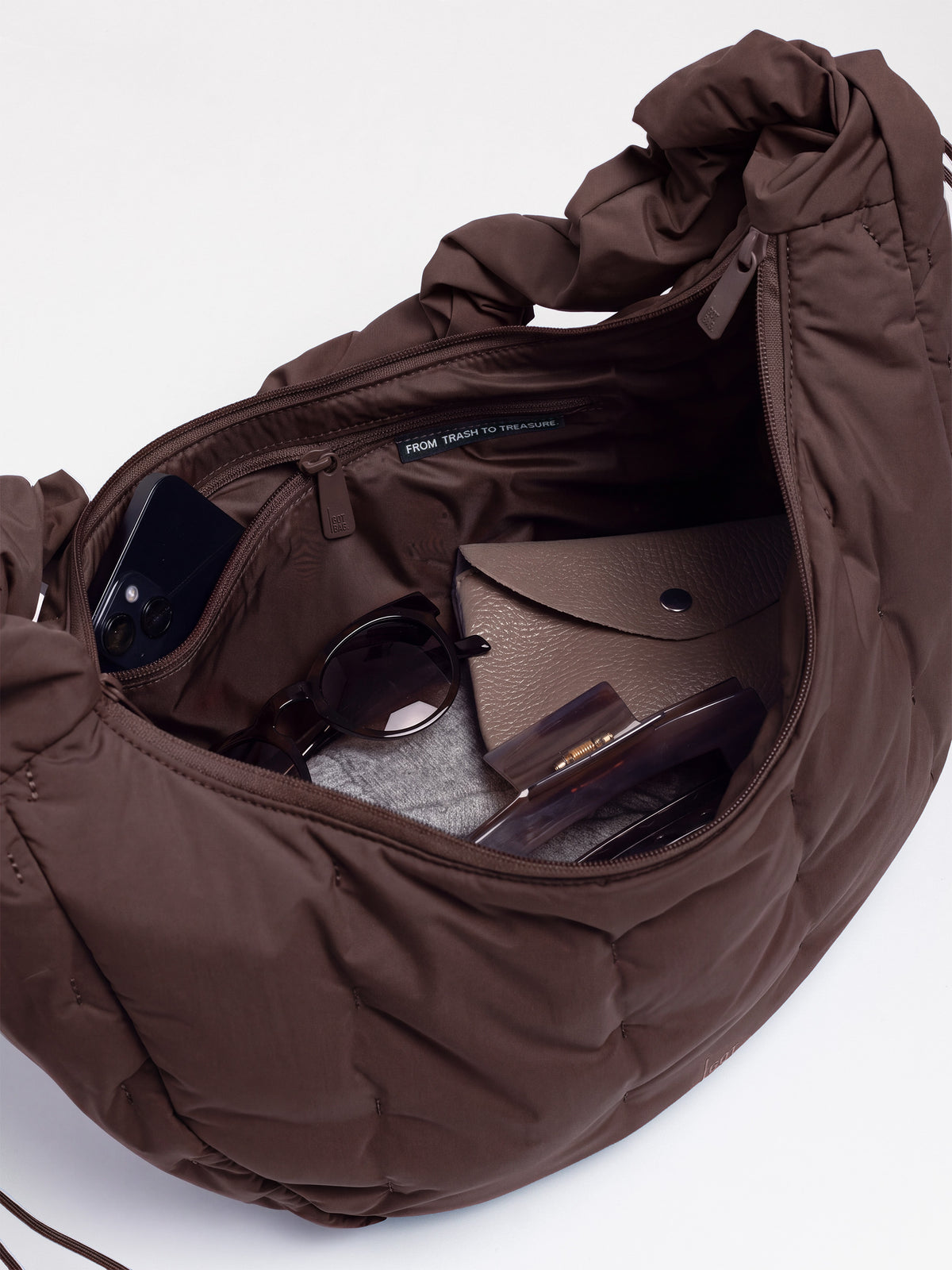 LOOMI MOON BAG RUFFLE Tasche in sea lion (dunkles Schokobraun) als Detailaufnahme des geöffneten Innenraums mit Gegenständen.