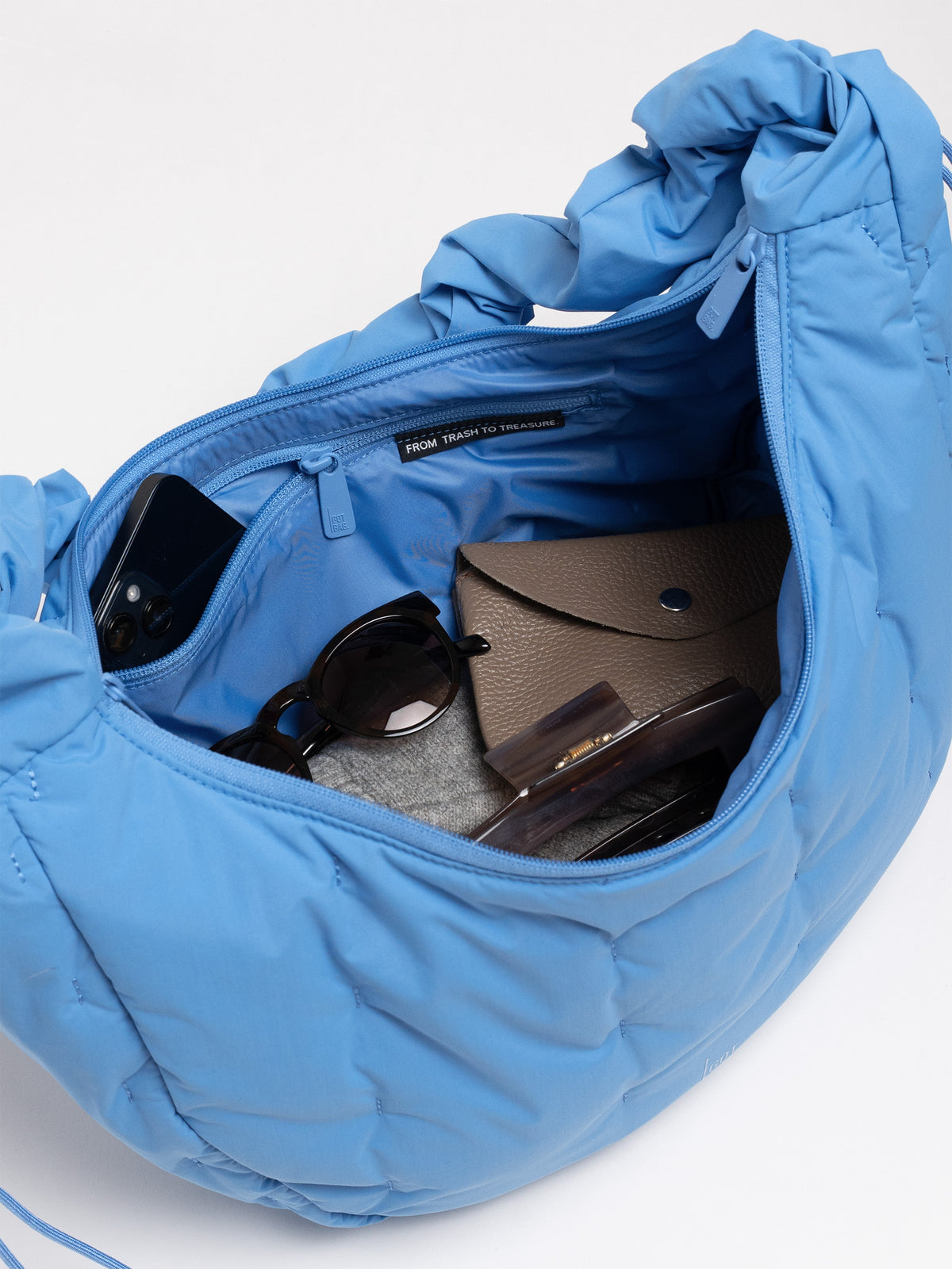 LOOMI MOON BAG RUFFLE Tasche in indigo wave, Innenansicht mit Handy, Sonnenbrille und Portemonnaie.
