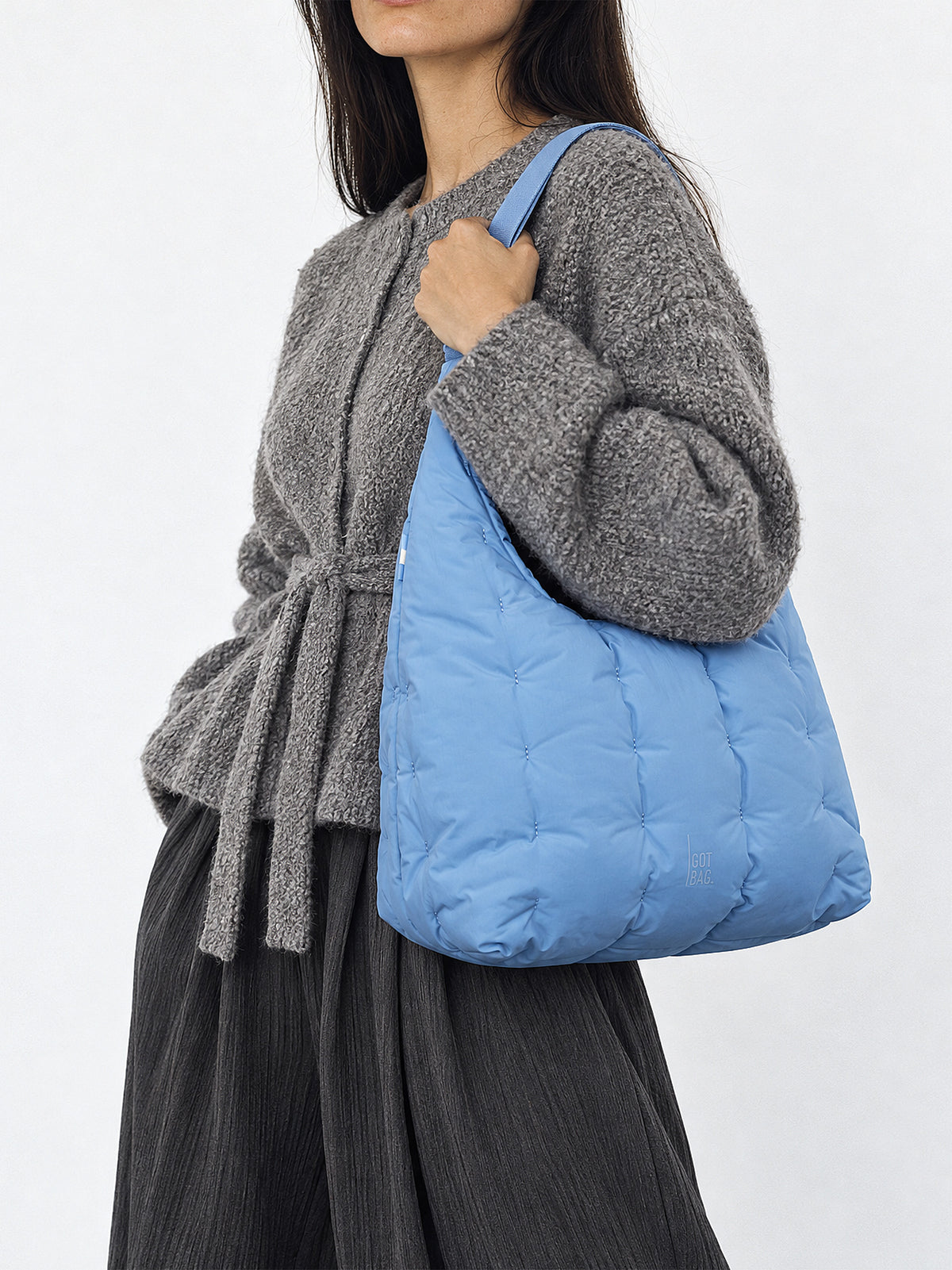 LOOMI SHOULDER BAG Tasche in indigo wave (warmes Hellblau) von einer Frau über der Schulter getragen.