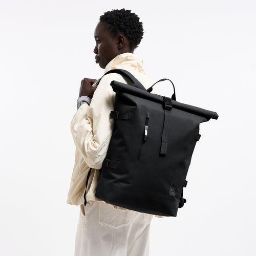 ROLLTOP Rucksack in black (Schwarz) von einer Frau auf dem Rücken getragen.