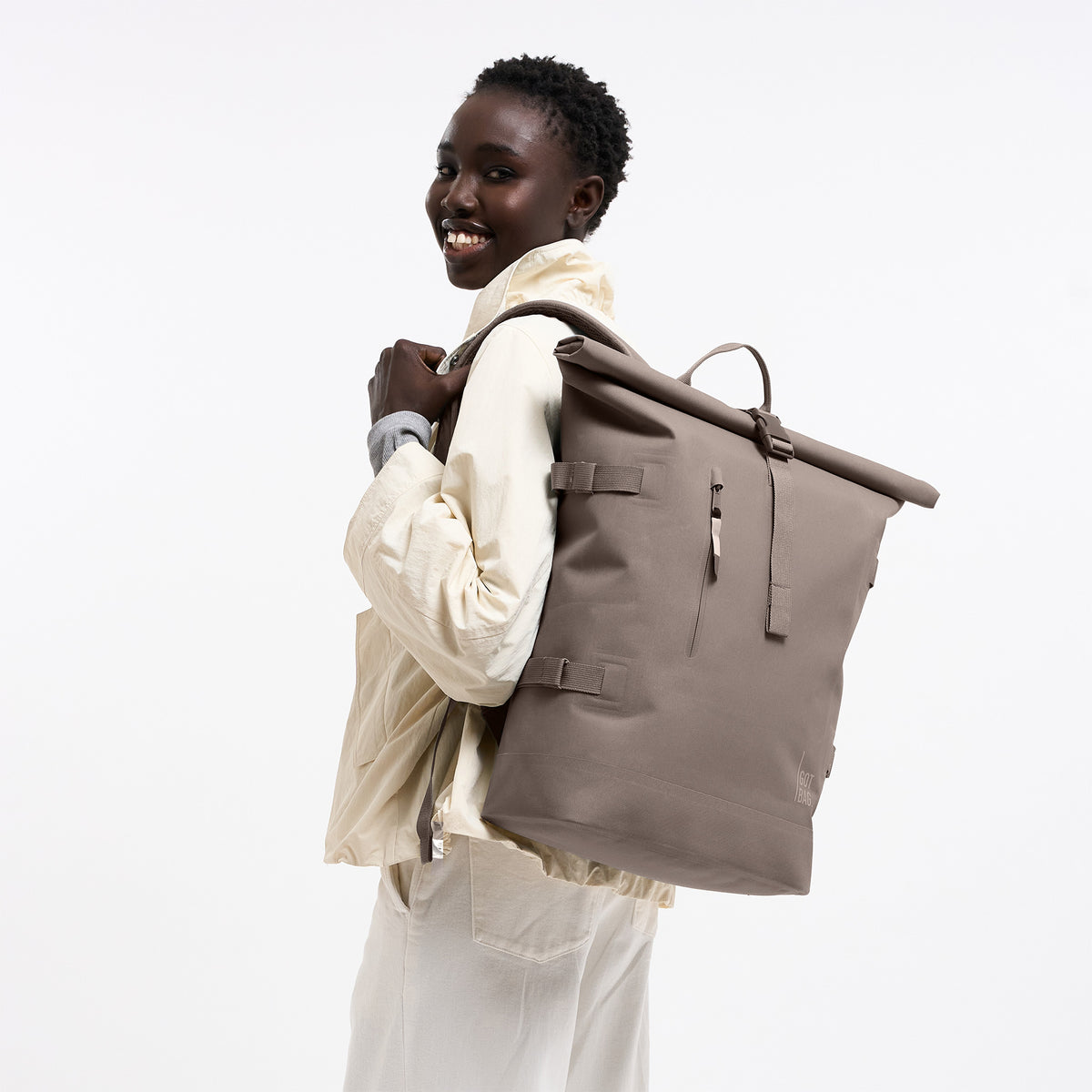 ROLLTOP 2.0 MONOCHROME Rucksack in oyster (klassisches Taupe-Braun) von einer Frau als Rucksack auf dem Rücken getragen.