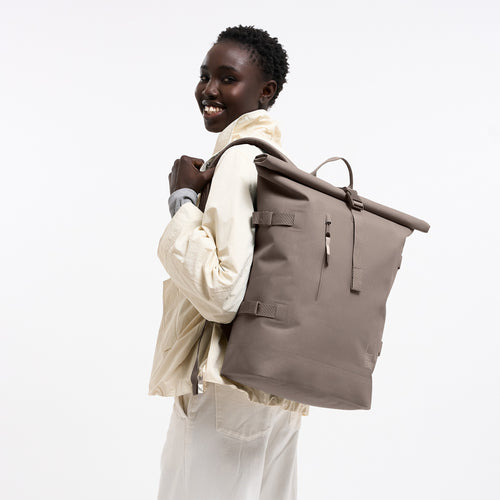 ROLLTOP 2.0 MONOCHROME Rucksack in oyster (klassisches Taupe-Braun) von einer Frau als Rucksack auf dem Rücken getragen.