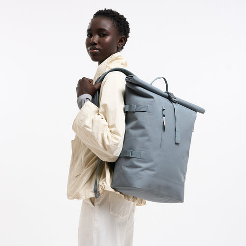 ROLLTOP 2.0 MONOCHROME Rucksack in marlin (grau-blau) von einer Frau getragen.