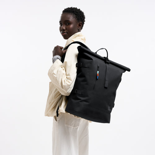 ROLLTOP Rucksack in black (Schwarz) von einer Frau auf dem Rücken getragen.