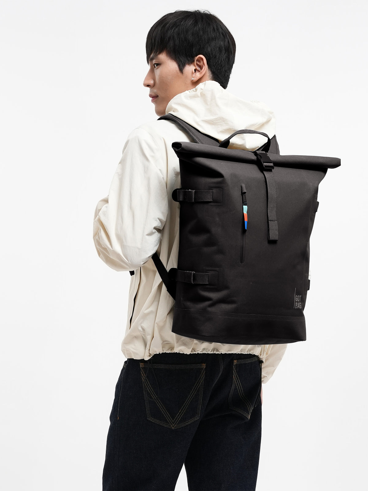 BP0012XX ROLLTOP Rucksack in mussel (dunkles Braun-Grau) von einem Mann auf dem Rücken getragen.