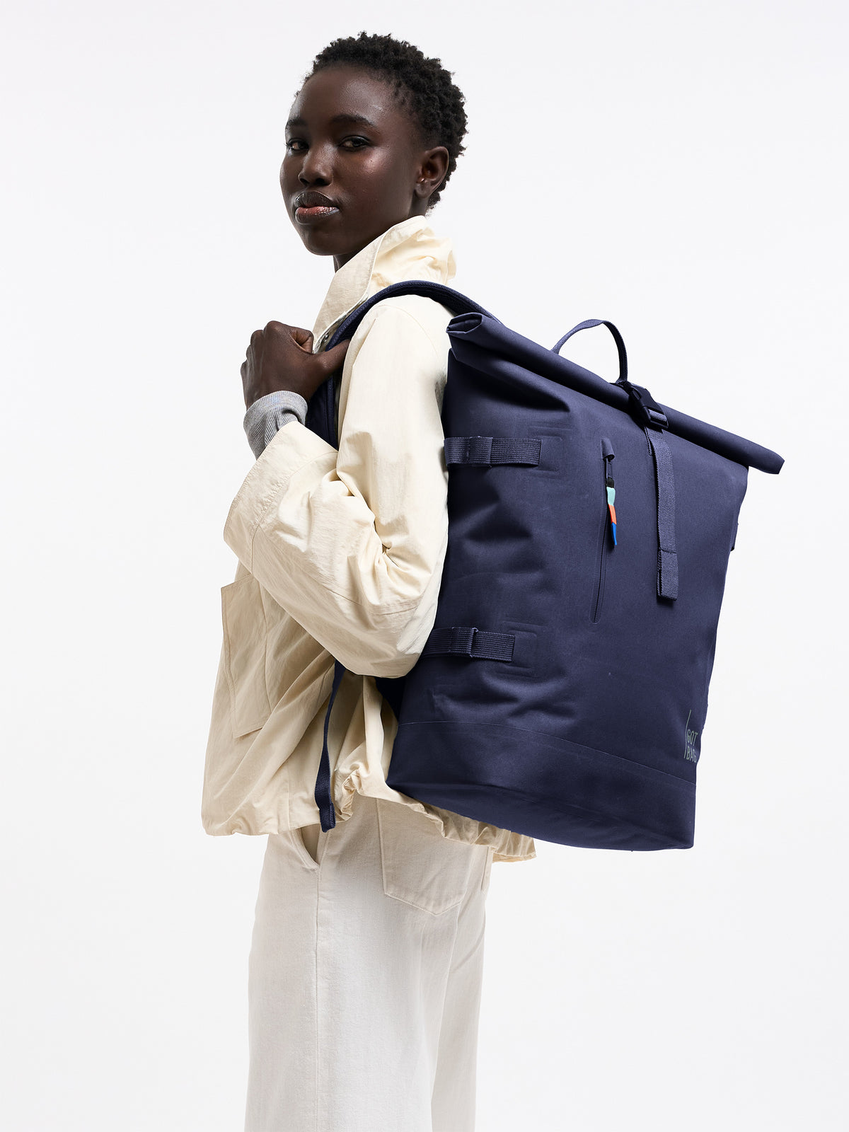ROLLTOP Rucksack in tide (tiefes Dunkelblau mit Lilastich) von einer Frau auf dem Rücken getragen.
