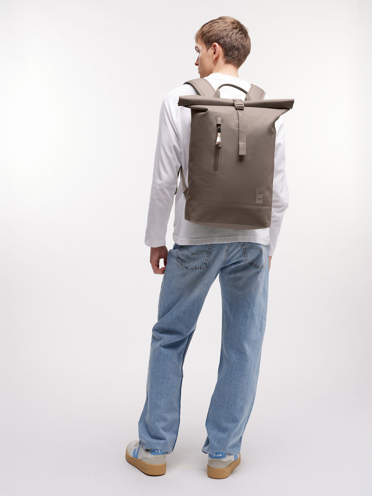 ROLLTOP LITE 2.0 MONOCHROME Rucksack in oyster (klassisches Taupe-Braun) von einem Mann auf dem Rücken getragen.