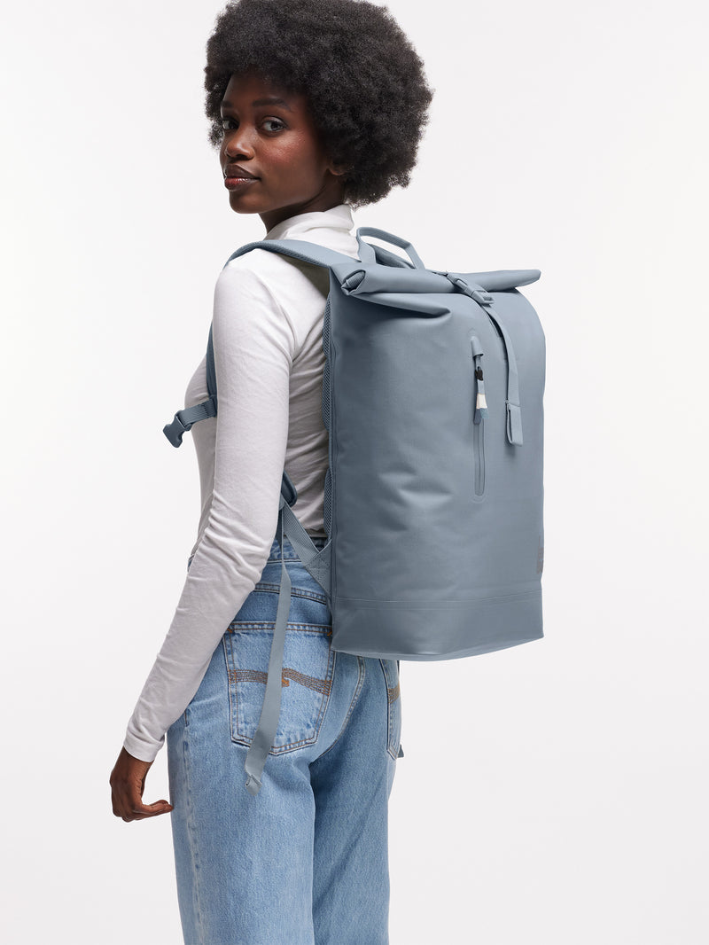 ROLLTOP LITE 2.0 MONOCHROME Rucksack in marlin (grau-blau) von einer Frau auf dem Rücken getragen.