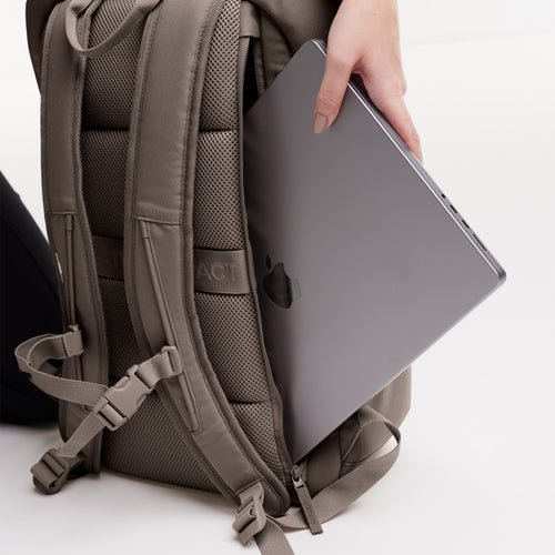 BP0083MO PRO PACK MONOCHROME Rucksack in oyster (klassisches Taupe-Braun), eine Hand steckt einen Laptop hinein.
