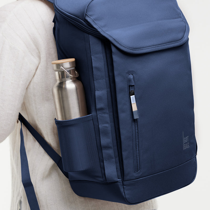 PRO PACK MONOCHROME Rucksack in deep ocean (dunkles Marineblau) auf dem Rücken getragen, mit einer Trinkflasche in der Seitentasche.