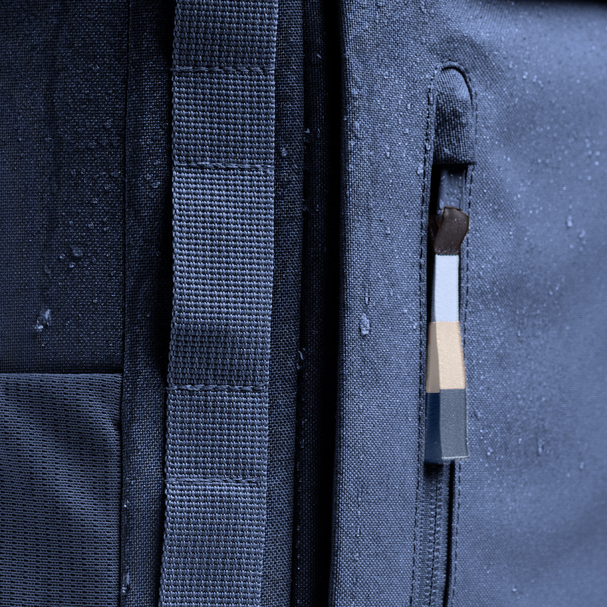 BP0083MO PRO PACK MONOCHROME Rucksack in deep ocean (dunkles Marineblau). Detail der wasserabweisenden Oberfläche mit Wassertropfen und Reißverschluss.