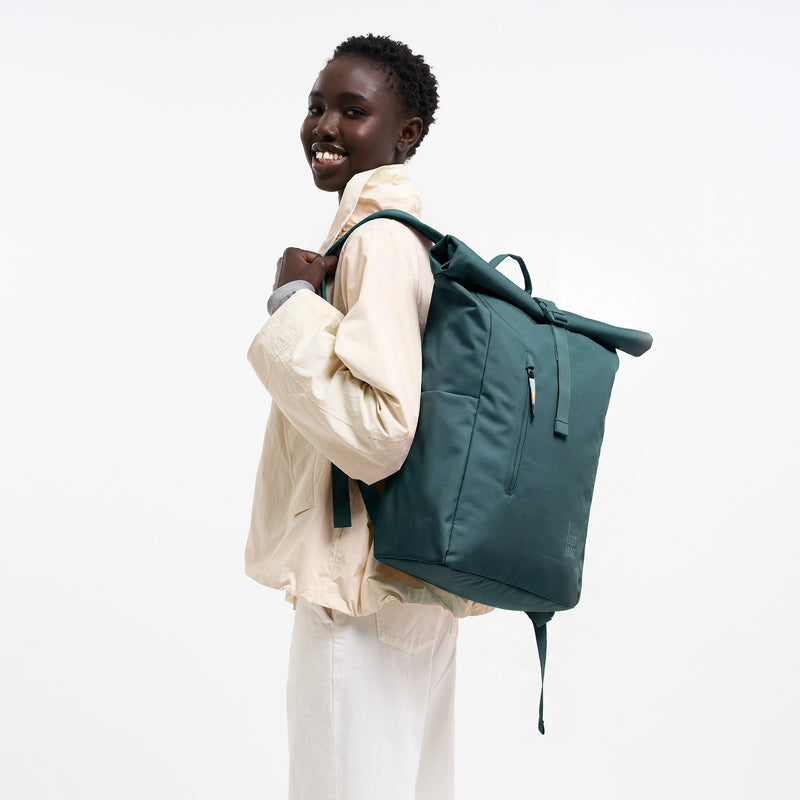 ROLLTOP EASY MONOCHROME Rucksack in sea teal (kühles Türkisgrün) von einer Frau als Rucksack auf dem Rücken getragen.