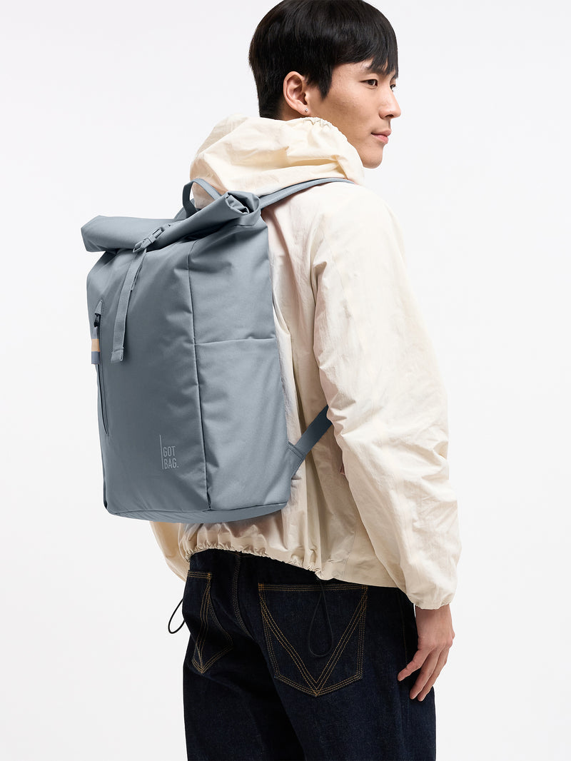 ROLLTOP EASY MONOCHROME Rucksack in marlin (grau-blau) von einem Mann als Rucksack auf dem Rücken getragen.