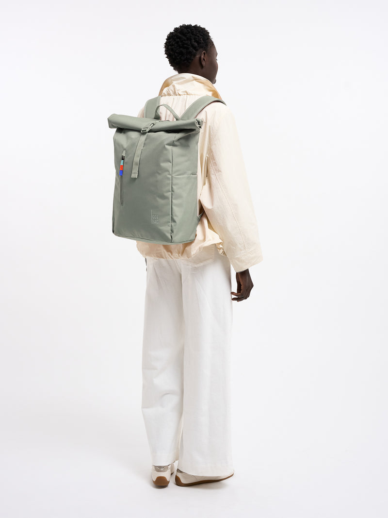 ROLLTOP EASY Rucksack in bass (Salbeigrün) von einer Frau als Rucksack auf dem Rücken getragen.