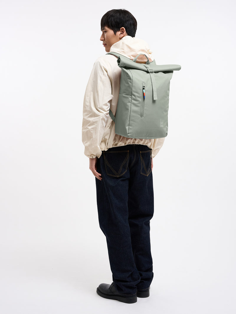 ROLLTOP EASY Rucksack in bass (Salbeigrün) von einem Mann als Rucksack auf dem Rücken getragen.