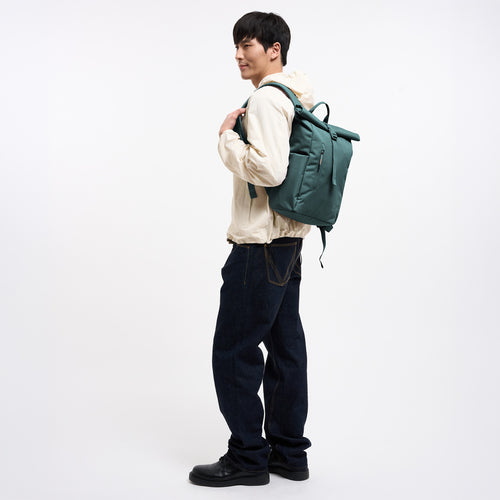 ROLLTOP EASY SMALL MONOCHROME Rucksack in sea teal (kühles Türkisgrün) von einem Mann auf dem Rücken getragen.