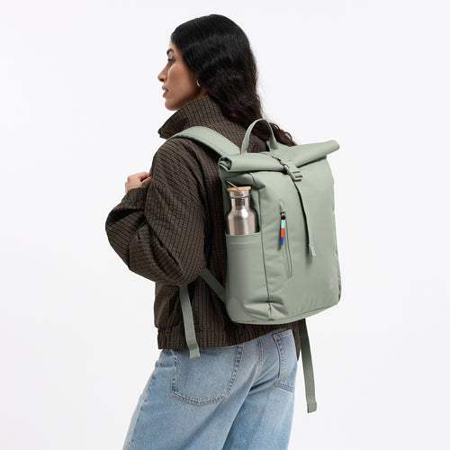 ROLLTOP EASY SMALL Rucksack in bass (Salbeigrün) von einer Frau als Rucksack auf dem Rücken getragen, mit Trinkflasche in der Seitentasche.