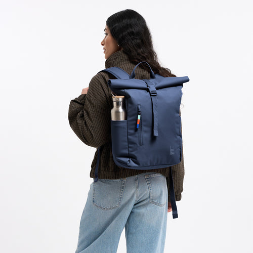 ROLLTOP EASY SMALL Rucksack in deep ocean (dunkles Marineblau) von einer Frau auf dem Rücken getragen.