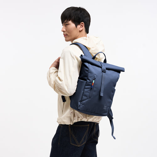 ROLLTOP EASY SMALL Rucksack in deep ocean (dunkles Marineblau) von einem Mann als Rucksack auf dem Rücken getragen.